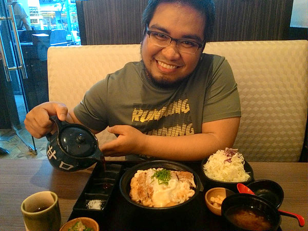 Ethan dining on Pork Katsudon Set with a teapot of sauce in hand