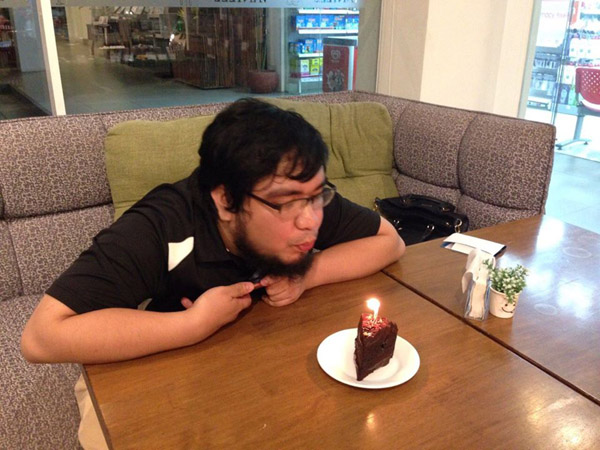 Birthday boy blowing candle on a slice of chocolate ganache